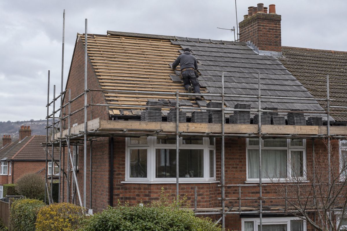 Semi-detached house mid re-roof with scaffold, bare battens and stacked new tiles
